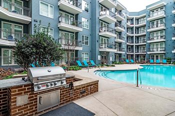 a barbecue grill sits next to a swimming pool in front of an apartment building